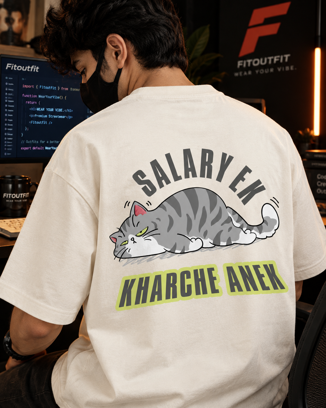 A man wearing a off white colored t-shirt with a humorous graphic on the back. The graphic features a sleeping gray tabby cat with the text 'SALARYEK' above it and 'KHARCHE ANEK' below it in black letters with a lime green outline.