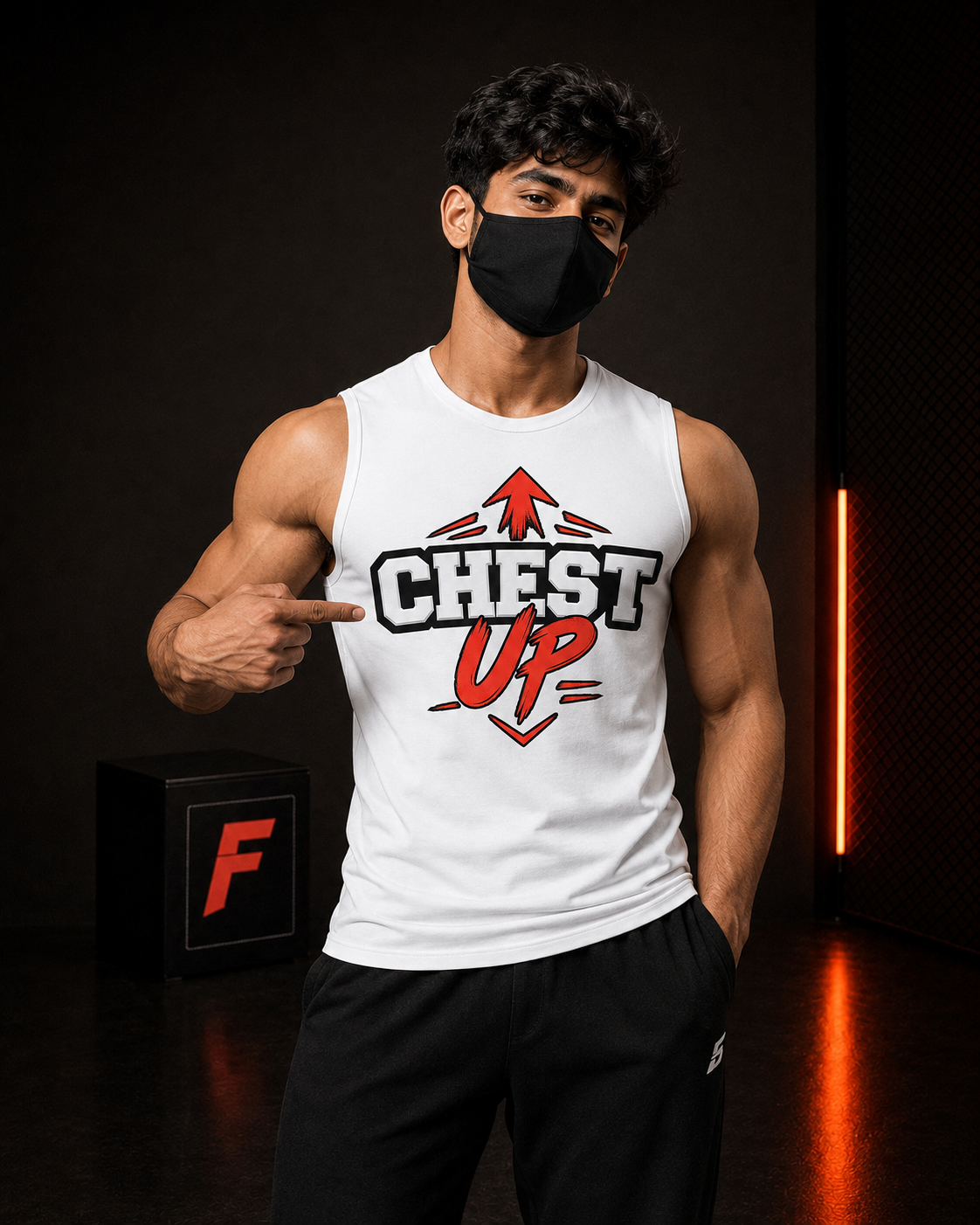 A man wearing a white sleeveless tank top with a red and black 'CHEST UP' graphic, paired with black athletic pants, standing in a dark gym setting and pointing to the chest graphic.
